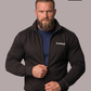 Bärtiger Mann in schwarzer Sweatjacke mit Stehkragen, weißem Brustaufdruck „Standhaft“ und blauem Unterziehtshirt.