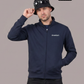 Ein Mann trägt eine dunkelblaue Trainingsjacke mit einem kleinen, weißen „Standhaft“-Schriftzug auf der linken Brust.
