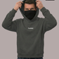 Mann mit Gesichtsmaske zieht Kapuze auf: dunkelgrauer Hoodie mit mittigem, weißem Schriftzug „Standhaft“, dazu Jeans.
