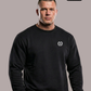 Kurzhaariger Mann im schwarzen Sweatshirt mit weißem Lorbeerkranz-Logo vor grauem Hintergrund.