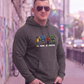Mann mit Sonnenbrille trägt einen grauen Hoodie mit „All Colors Are Beautiful“-Grafikprint in urbaner Umgebung.