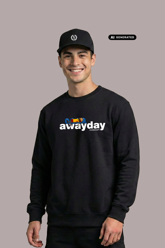Ein lächelnder Mann mit schwarzer Logo-Cap trägt einen schwarzen Pullover mit weißem „awayday standhaft“-Aufdruck vor einem schlichten, grauen Hintergrund.