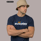 Ein Mann mit beigem Anglerhut und verschränkten Armen trägt ein dunkelblaues T-Shirt mit weißem „awayday“-Schriftzug.