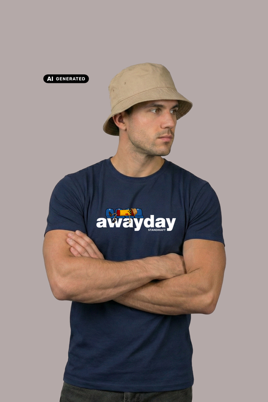 Ein Mann mit beigem Anglerhut und verschränkten Armen trägt ein dunkelblaues T-Shirt mit weißem „awayday“-Schriftzug.
