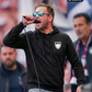 Ein Mann mit Sonnenbrille spricht oder singt in ein Mikrofon im Stadion und trägt einen schwarzen Hoodie mit einem weißen Wappen-Logo samt Adlergrafik und „STANDHAFT“-Schriftzug auf der linken Brust.