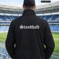 Ein Mann von hinten in einer schwarzen Bomberjacke mit weißem „Standhaft“-Schriftzug im altdeutschen Stil auf dem Rücken.