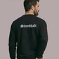 Ein Mann von hinten in einem schwarzen Pullover mit weißem „Standhaft“-Schriftzug im altdeutschen Stil auf dem Rücken.