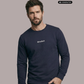 Ein Mann trägt einen dunkelblauen Pullover mit einem kleinen, weißen „Standhaft“-Schriftzug auf der Brust.