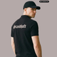 Ein Mann von hinten in einem schwarzen Poloshirt mit weißem „Standhaft“-Schriftzug im altdeutschen Stil auf dem Rücken.