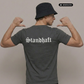 Ein Mann von hinten mit Anglerhut und dunkelgrauem T-Shirt mit weißem „Standhaft“-Schriftzug im altdeutschen Stil auf dem Rücken.
