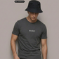 Ein Mann mit Anglerhut trägt ein dunkelgraues T-Shirt mit einem kleinen, weißen „Standhaft“-Schriftzug auf der Brust.