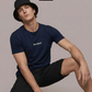 Ein Mann mit Anglerhut trägt ein dunkelblaues T-Shirt mit einem kleinen, weißen „Standhaft“-Schriftzug auf der Brust.