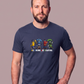 Mann trägt dunkelblaues T-Shirt mit buntem „All Colors Are Beautiful“-Grafikprint vor neutralem Hintergrund.