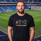 Mann im Stadion trägt schwarzes T-Shirt mit buntem „All Colors Are Beautiful“-Grafikprint und Ultras-Motiven.