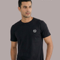 Mann im schwarzen T-Shirt mit weißem Lorbeerkranz-Logo, Hände in den Taschen, dazu khakifarbene Cargohose.