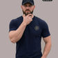 Ein nachdenklicher Mann mit einer schwarzen Basecap samt weißem „Standhaft“-Schriftzug trägt ein dunkelblaues T-Shirt mit einem kreisförmigen, gelb-blauen „STANDHAFT“-Logo samt kleiner Krone auf der linken Brust.