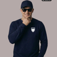 Ein lächelnder Mann mit dunkelblauer Basecap und Sonnenbrille trägt einen dunkelblauen Pullover mit einem weißen Wappen-Logo samt Adlergrafik und „STANDHAFT“-Schriftzug auf der linken Brust.