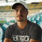 Mann mit Cap im grauen T-Shirt mit dem Aufdruck „STANDHAFT“ und vier Motivkarten vor Stadion-Tribüne.