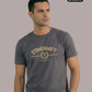 Ein Mann trägt ein dunkelgraues T-Shirt mit goldenem „STANDHAFT“-Schriftzug und Lorbeerkranz-Logo auf der Brust.