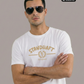 Ein Mann mit Sonnenbrille trägt ein weißes T-Shirt mit goldenem „STANDHAFT“-Schriftzug und Lorbeerkranz-Logo auf der Brust.