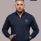 Ein Mann trägt eine dunkelblaue Trainingsjacke mit Reißverschluss und einem kreisförmigen, gelb-blauen „STANDHAFT“-Logo auf der linken Brust.