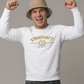Ein Mann mit beigem Anglerhut trägt einen weißen Pullover mit goldenem „STANDHAFT“-Schriftzug und Lorbeerkranz-Logo auf der Brust.