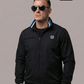 Mann mit Sonnenbrille in schwarzer Jacke mit Lorbeerkranz-Logo sowie blau-weißen Streifen an Kragen und Bündchen.