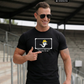 Ein Mann mit Sonnenbrille trägt ein schwarzes T-Shirt mit einer Comic-Grafik auf der Brust.