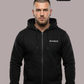Ein Mann trägt eine schwarze Zip-Jacke mit Kapuze und einem kleinen, weißen „Standhaft“-Schriftzug auf der linken Brust.