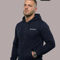 Ein Mann trägt eine dunkelblaue Zip-Jacke mit Kapuze und einem kleinen, weißen „Standhaft“-Schriftzug auf der linken Brust.